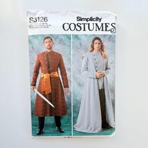 Może przedstawiać: Koperta z wykrojem krawieckim Simplicity Costumes S3126 przedstawiająca dwa wzory. Po lewej brązowy płaszcz z długim rękawem, złotą szarfą i mieczem. Po prawej jasnoszary płaszcz z długim rękawem i guzikami. Tekst zawiera S3126 oraz COSTUMES.