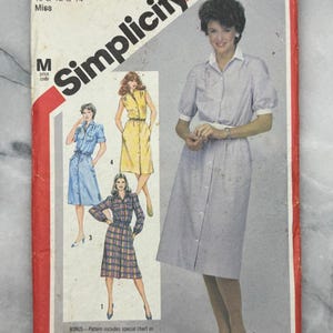 May include: Vintage Simplicity sewing pattern, size N, for Miss sizes 10, 12, and 14. The pattern features a button-down dress with short sleeves. The cover includes illustrations of the finished garments and the number 6375.