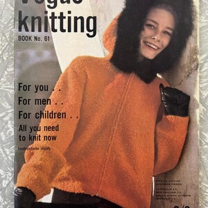 May include: Vintage Vogue Knitting Book No. 61 cover. The cover features a woman wearing an orange hooded coat with a black fur trim and black gloves. The cover text includes "Vogue knitting" and "For you, For men, For children."