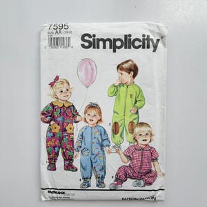 May include: A Simplicity sewing pattern envelope, number 7595, size AA (1/2-2). The front features illustrations of children wearing various one-piece jumpsuits and rompers with colourful patterns, including a pink balloon and football-themed patches.