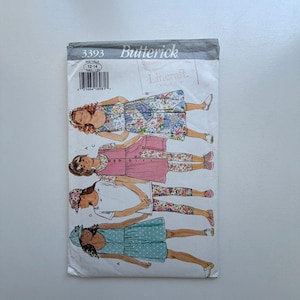 May include: A Butterick sewing pattern, size 12-14, featuring illustrations of girls' clothing designs. The designs include dresses, tops, and leggings in various patterns and colors. The pattern's cover is primarily white and gray.