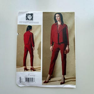 May include: Vogue Patterns sewing pattern by Anne Klein. The pattern features a red suit with a jacket and trousers. The pattern includes the Anne Klein logo and the text "Vogue Patterns American Designer". The pattern size is ES (14-16-18-20-22).