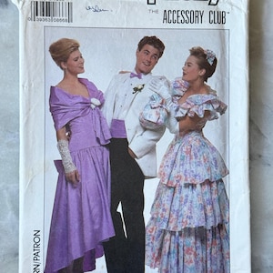May include: Simplicity sewing pattern for formal wear. The cover features three people in prom attire. The woman on the left wears a purple dress and shawl. The man in the center wears a white tuxedo. The woman on the right wears a floral dress.