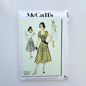 Peut inclure: Une pochette de patron de couture McCall's M8357 illustrant deux styles de robes. Le devant présente une robe à chevrons jaunes et noirs avec une encolure carrée et une robe à col blanc avec une jupe à chevrons. Le texte inclut VINTAGE 50's.