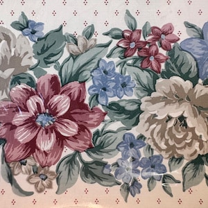 May include: Floral wallpaper border with a repeating pattern of large, colourful flowers. The flowers are in shades of pink, blue, and cream, with green leaves. The background is a light cream colour with small, dotted accents. A burgundy stripe borders the top and bottom.