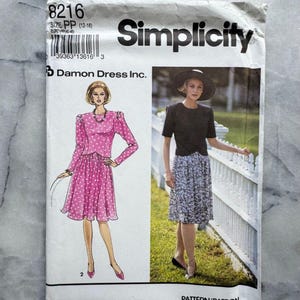 Può includere: Un modello di cucito Simplicity vintage, taglia PP (12-18), con illustrazioni di abiti. Il pacchetto del modello ha il numero 8216 e il testo "Simplicity" in grassetto nero. È visibile anche il logo Damon Dress Inc.