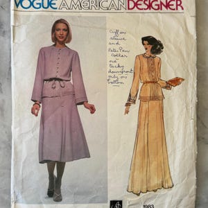 May include: A vintage Vogue American Designer sewing pattern. The cover displays illustrations of two outfits, including a skirt suit and a long dress. The text reads "VOGUE AMERICAN DESIGNER", "Albert Nipon 1983", and includes handwritten notes about the design.