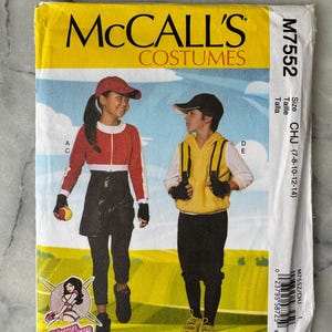 May include: A McCall's Costumes sewing pattern, M7552, featuring illustrations of two children in baseball-themed outfits. The pattern includes sizes CHJ (7-8-10-12-14). The cover is yellow with a blue sky background.