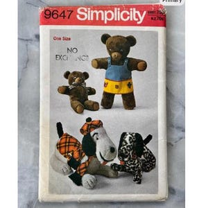 May include: A vintage Simplicity sewing pattern with illustrations of stuffed bears and dogs. The pattern cover is red and white, with the number 9647. The bears wear overalls and the dogs wear hats and scarves. The pattern is for one size.
