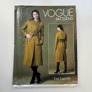 Könnte beinhalten: Vogue Patterns Schnittmuster V1650 mit einem Design von Guy Laroche. Das Cover zeigt eine Frau in einem langen, olivgrünen Trenchcoat mit Gürtel und schwarzen Stiefeln. Das Vogue Patterns-Logo befindet sich oben.