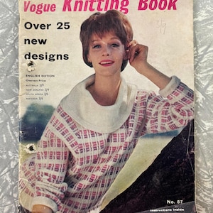 Könnte beinhalten: Vintage Vogue Strickbuch-Cover mit einer Frau in einem rosa-weiß gemusterten Pullover. Auf dem Cover steht "Vogue Knitting Book" in Pink, darunter "Over 25 new designs". Das Buch ist die englische Ausgabe, Nr. 57.