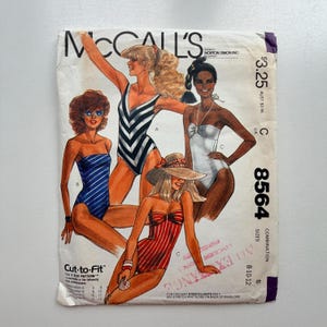 May include: Vintage McCall's sewing pattern envelope featuring illustrations of women in swimsuits. The swimsuits are in various styles, including striped and solid colors. The envelope includes the text "Cut-to-Fit" and the pattern number 8564.