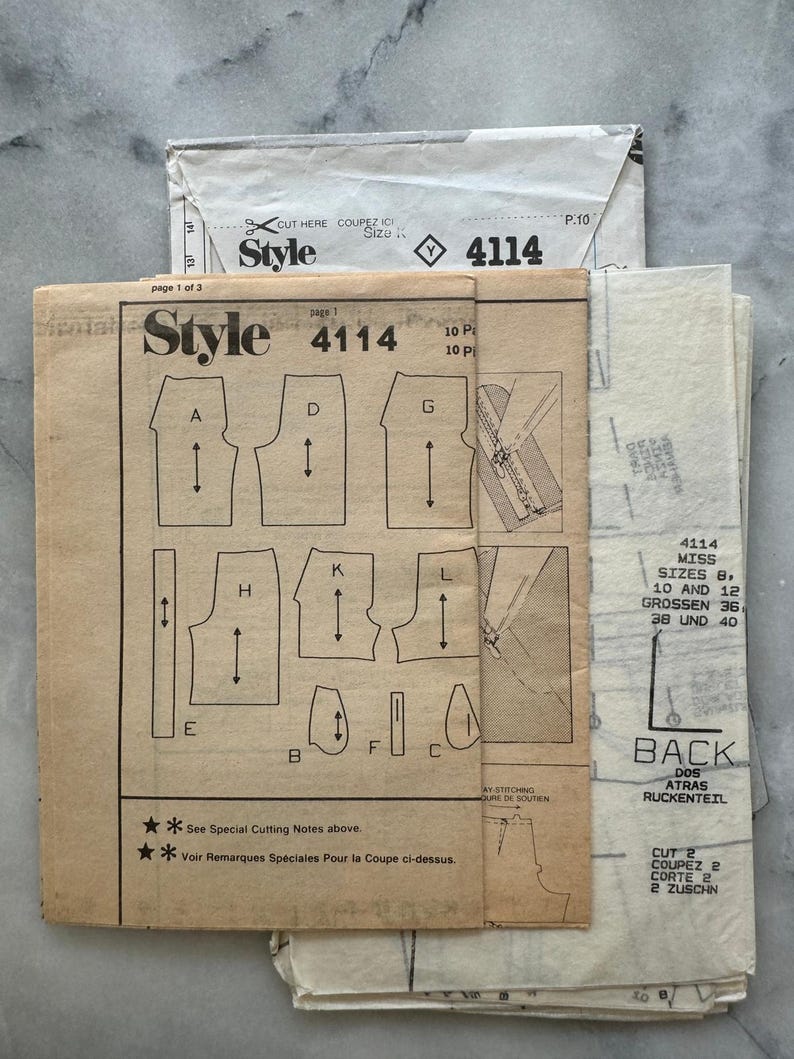 May include: A collection of vintage sewing patterns, featuring the "Style 4114" design. The patterns include diagrams and instructions for garment construction. The paper is aged with visible text and illustrations, offering a glimpse into classic sewing techniques.