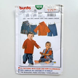 Pode incluir: Um envelope de molde de costura Burda 9698 para roupas infantis. A frente exibe ilustrações de uma jaqueta com capuz e calças, juntamente com fotografias de duas crianças vestindo as peças. O texto inclui os tamanhos 74-98 e 3M-3Y.