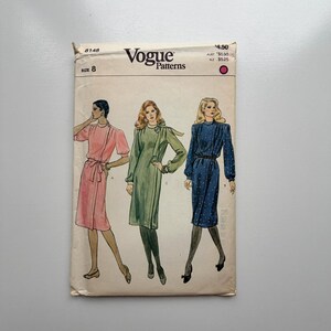 Peut inclure: Patron de couture Vogue vintage avec illustrations de trois robes. L'enveloppe crème porte le logo Vogue et la taille 8. Les robes sont roses, vertes et bleues, chacune avec des designs et des détails uniques.