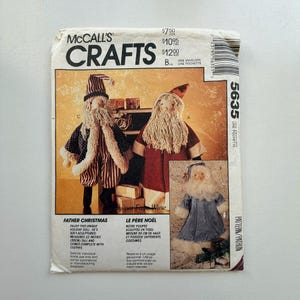 May include: McCall's Crafts pattern for Father Christmas dolls. The pattern includes instructions for soft-sculpted dolls that measure 55cm tall and come with clothes. The envelope features images of the finished dolls.