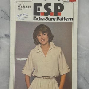 May include: Vintage Simplicity ESP Extra-Sure Pattern 8510, size N (10, 12, & 14) Miss. The pattern shows a woman in a light-coloured dress with a collared neckline and a belt. The cover includes the text "NORMS."