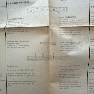 May include: A folded paper sewing pattern with detailed instructions and diagrams for waistband and carrier construction. The text includes measurements in inches and fractions of an inch, along with sewing techniques.