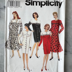 Op de afbeelding: Simplicity naaipatroon 8115. De omslag toont illustraties van vijf verschillende jurk ontwerpen. De jurken zijn in verschillende kleuren en patronen, waaronder zwart-wit, rood met zwarte stippen en effen wit en zwart. Maat PP (12-18).