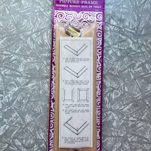 Puede incluir: Un kit de marco de fotos vintage "Rulex one minute". El embalaje es morado y blanco, con instrucciones y hardware visibles. El texto en el paquete dice "Montaje sin pegamento ni herramientas".