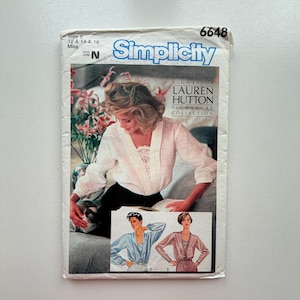 May include: A vintage Simplicity sewing pattern showing a woman in a white blouse with lace. The pattern includes the text "LAUREN HUTTON SIGNATURE COLLECTION" and size details. The pattern number is 6648.