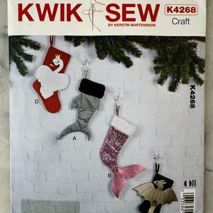 May include: A Kwik Sew craft pattern, K4268, showing four Christmas stocking ornaments. The ornaments include a swan, a shark, a mermaid, and a dragon. The pattern is by Kerstin Martensson.