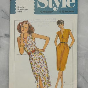 May include: Vintage sewing pattern titled "Style" featuring illustrations of two dresses. The pattern includes sizing information: Size 14, Bust 92 cm. The cover has a blue and white design with the number "3034" and the word "Style".