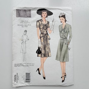 May include: A Vogue Vintage Model sewing pattern envelope for a 1943 design, labeled V2876. The front displays illustrations of two wrap-style dresses, one with short sleeves and a floral print, and one with long sleeves in a solid muted green color.