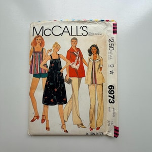 May include: Vintage McCall's sewing pattern with illustrations of four outfits. The pattern cover includes the text "McCall's", the price, and the pattern number 6973. The illustrations depict a variety of 1970s fashion styles.