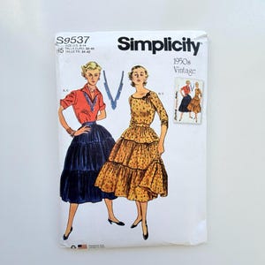 May include: A Simplicity S9537 sewing pattern envelope for 1950s vintage clothing. The front displays illustrations of two outfits: a red collared blouse with a dark blue tiered skirt, and a yellow floral print dress with a bow at the neckline.