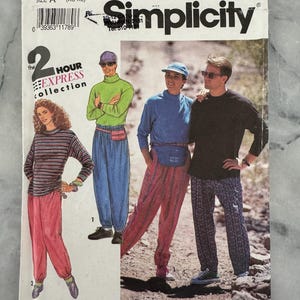 May include: Simplicity sewing pattern 7526, featuring a 2-hour express collection. The cover shows illustrations of people wearing various outfits, including a striped top with pink pants, a green turtleneck with blue pants, and a blue top with red pants.