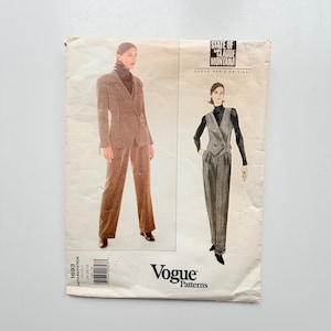 Könnte beinhalten: Eine Vogue Patterns Schnittmusterhülle, Nummer 1693, mit State of Claude Montana Designs. Das Cover zeigt Illustrationen eines braunen Blazer- und Hosensets sowie eines grauen Westen- und Hosensets, jeweils kombiniert mit dunklen Rollkragenpullovern.