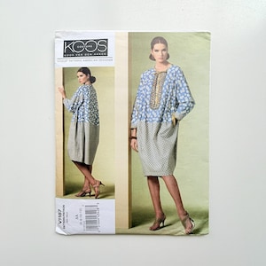 May include: A Koos Couture Vogue Patterns American Designer sewing pattern envelope, model V1187, featuring a knee-length dress with a blue and white floral upper section, a patterned lower section, and a decorative trim along the centre neckline.