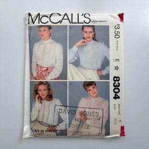 May include: A vintage McCall's sewing pattern packet showing four blouse designs. The packet is white with the McCall's logo and pattern number 8304. The price is £2.70. The bust size is 80 cm.