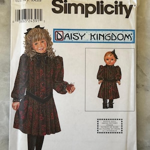 May include: Simplicity sewing pattern featuring a dress design from Daisy Kingdom. The pattern includes sizes 3, 4, 5, and 6. The cover shows a girl in a paisley dress and a doll in a matching dress. The pattern includes a bonus doll dress pattern.