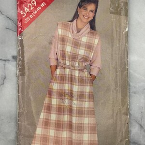 May include: Vintage sewing pattern featuring a woman in a pink and white plaid dress. The pattern cover displays "See & Sew" and "5429". The dress has a matching belt, cowl neck, and long sleeves. The pattern is for sizes B (14-16-18).