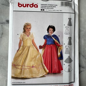 Può includere: Una busta per cartamodelli Burda con due bambine in costume da principessa. La busta ha il numero 2480 e testo in più lingue. Gli abiti sono gialli e rossi.