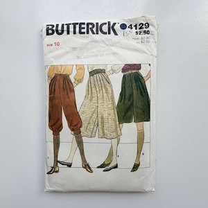 May include: A Butterick 4129 sewing pattern envelope for size 10. The front features illustrations of three different pant styles: rust-colored tapered pants, a beige textured culotte, and dark green knee-length shorts, all paired with socks and shoes.