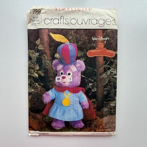 May include: A Simplicity pattern for a Walt Disney's Gummi Bears plush toy. The pattern features a purple bear wearing a blue and red hat, glasses, a blue tunic, and a red cape. The pattern is labeled "7788" and "One Size".