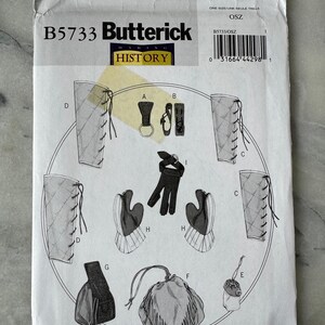 May include: A Butterick sewing pattern, B5733, featuring illustrations of historical costume elements. The pattern includes diagrams of various pieces, such as gloves, pouches, and leg coverings, with lacing details. The pattern is labeled "HISTORY".