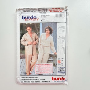 May include: A Burda Easy sewing pattern envelope 2683 for pyjamas. The front shows two people wearing pyjama sets, one in a tan checkered print and one in solid beige. Text includes Burda Easy, Schlafanzug, and a fire warning label.