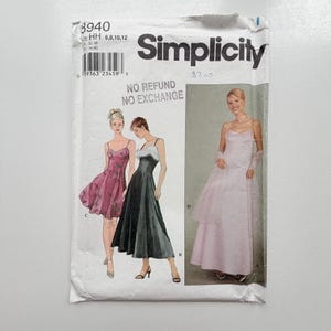 Könnte beinhalten: Eine Simplicity Schnittmusterhülle, Nummer 8940, Größe HH 6, 8, 10, 12. Die Vorderseite zeigt Illustrationen von drei Kleidern: ein kurzes rosa Blumenkleid, ein schwarzes Midikleid mit weißem Kunstfellbesatz und ein langes hellrosa Abendkleid.