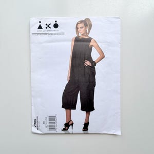 May include: A Vogue Patterns American Designer sewing pattern envelope for a black sleeveless jumpsuit with a wide-leg, cropped silhouette. The front features the text "iko andreakatzobjects" and "V1185" with a barcode and size range 8-10-12-14.
