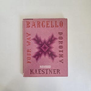 May include: A hardcover book titled Bargello Four Way by Dorothy Kaestner, Revised. The cover is a dusty rose color with a dark purple, cross-shaped geometric needlepoint pattern in the center. The text is printed in a dark purple, pixelated font.