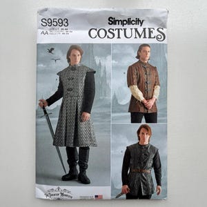 May include: Simplicity Costumes sewing pattern featuring medieval costume designs. The pattern includes illustrations of various outfits, including a long coat with a patterned vest, a brown tunic, and a vest with a belt. The pattern is designed and printed in the USA.