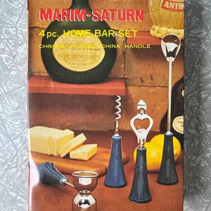 Könnte beinhalten: Ein Vintage "MARIM-SATURN" 4-teiliges Home-Bar-Set. Die Box zeigt eine dunkelgrüne Flasche, einen Korkenzieher, einen Flaschenöffner, einen Barlöffel und einen Doppel-Jigger. Die Werkzeuge haben verchromte Griffe und blaue Basen.