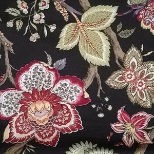 May include: Close-up of a fabric with a dark background and a floral pattern. The design features large, stylized flowers in shades of red, cream, and brown, along with green and tan leaves and branches. The overall aesthetic is reminiscent of vintage textiles.