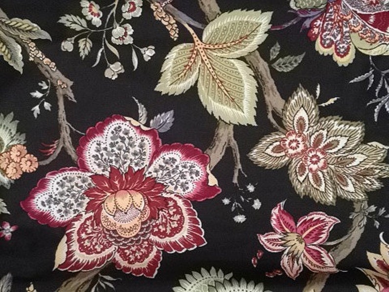 May include: Close-up of a fabric with a dark background and a floral pattern. The design features large, stylized flowers in shades of red, cream, and brown, along with green and tan leaves and branches. The overall aesthetic is reminiscent of vintage textiles.