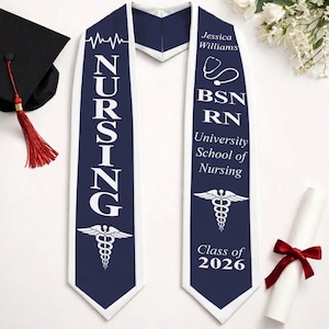 May include: A navy blue and white graduation sash with the word "NURSING" in large white letters. The sash includes the text "Jessica Williams", "BSN RN", "University School of Nursing", and "Class of 2026". A mortarboard and diploma are also present.