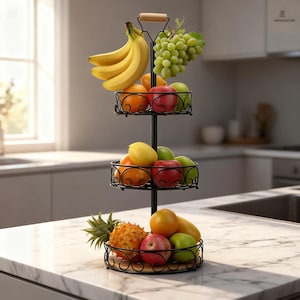 May include: A three-tiered black metal fruit basket filled with various fruits, including bananas, grapes, apples, oranges, and a pineapple. The basket has a wooden handle and sits on a marble countertop.